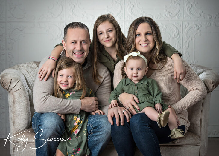Studio family portrait of mom, dad and three daughters looking at you smiling