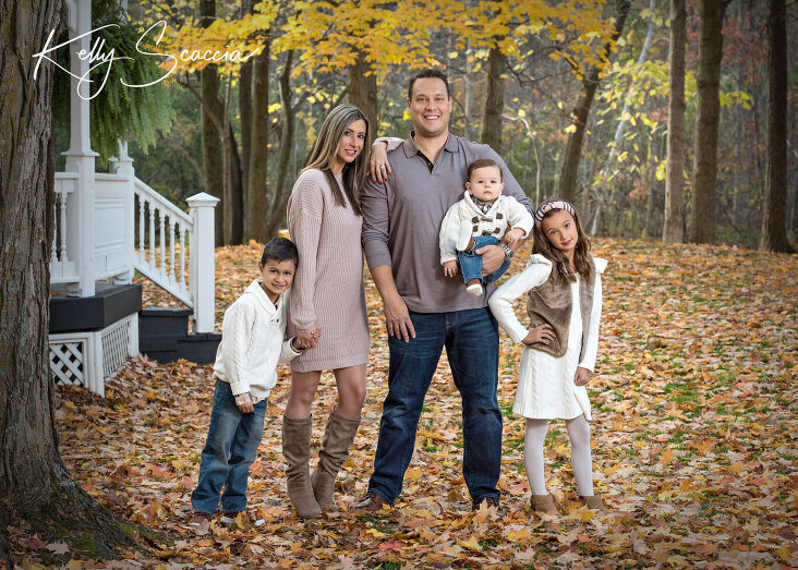 Outdoor fall family portrait of five wearing cream sweaters, looking at you, smiling