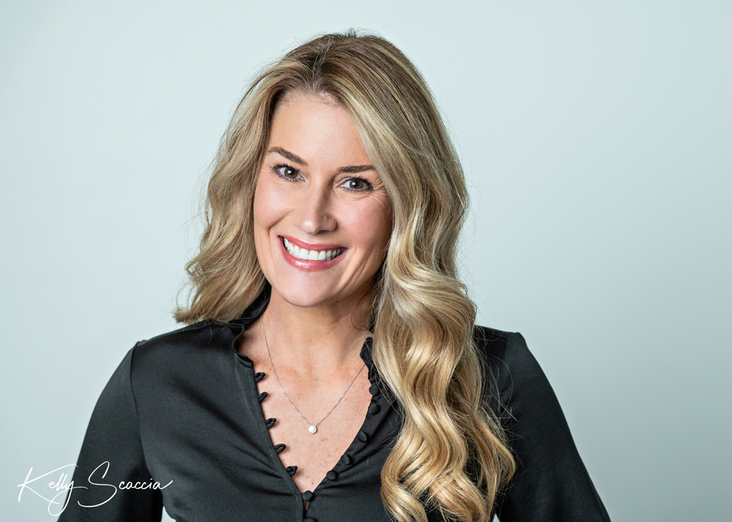 Studio female long blonde hair black shirt business headshot against white background smiling looking at you