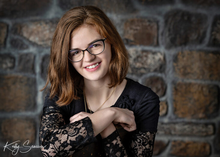 Senior girl studio portrait, short, red hair, glasses, black shirt, looking at you, smiling