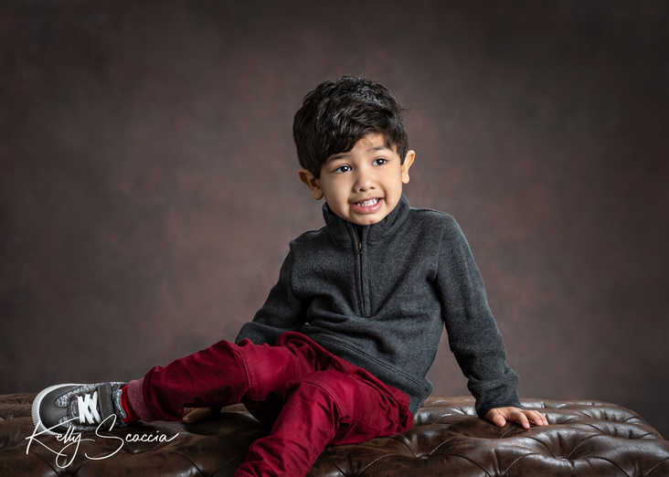 Studio portrait little boy, dark hair and eyes, looking up, wearing gray sweater