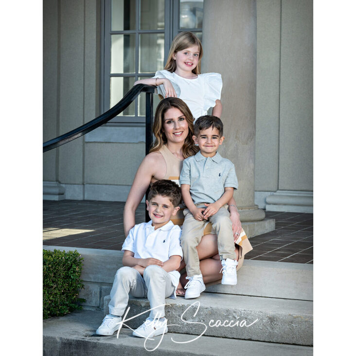 Outdoor mom and three kids portrait on steps looking at you smiling