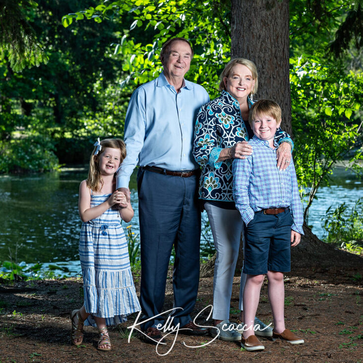 Outdoor portrait of grandma and grandpa smiling with one granddaughter and one grandson