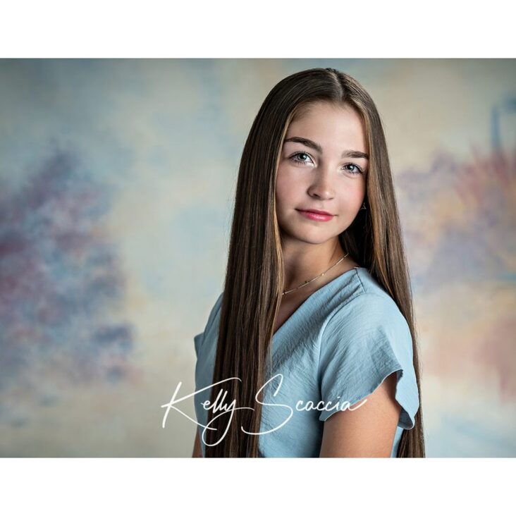 Studio high school senior girl portrait with long, dark brown hair, dark eyes, looking at you, wearing blue short dress, smiling