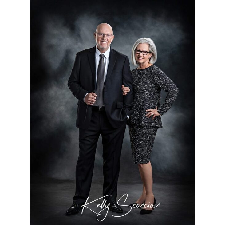 Indoor studio portrait of couple 50th anniversary formal wearing black suit and tie and skirt and top suit 