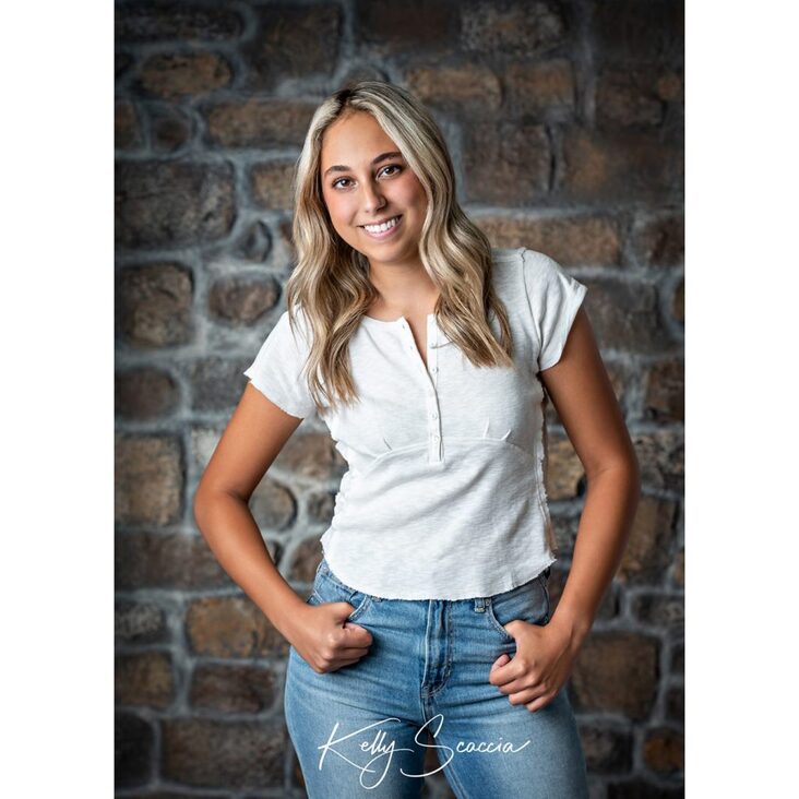 Indoor studio portrait high school senior girl long, blonde hair, brown eyes wearing jeans and cream shirt