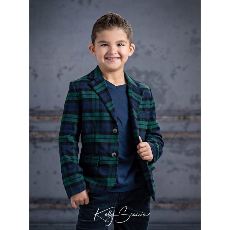 Indoor studio portrait young boy wearing blue and green striped jacket and black jeans