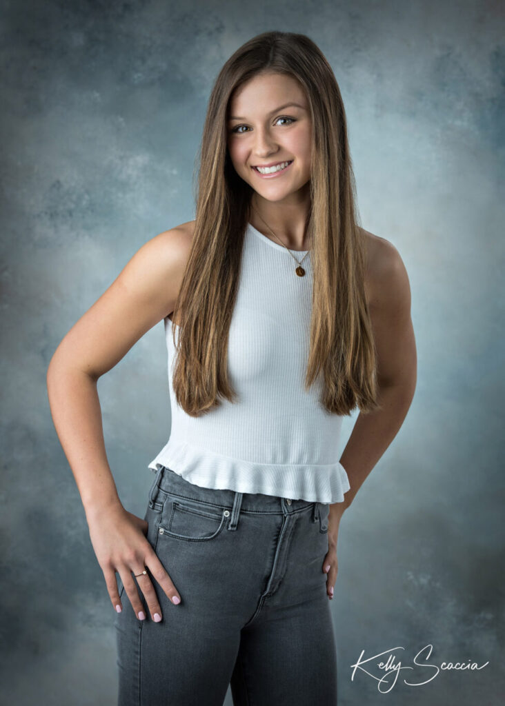 High School senior girl in studio portrait hands on hip smiling