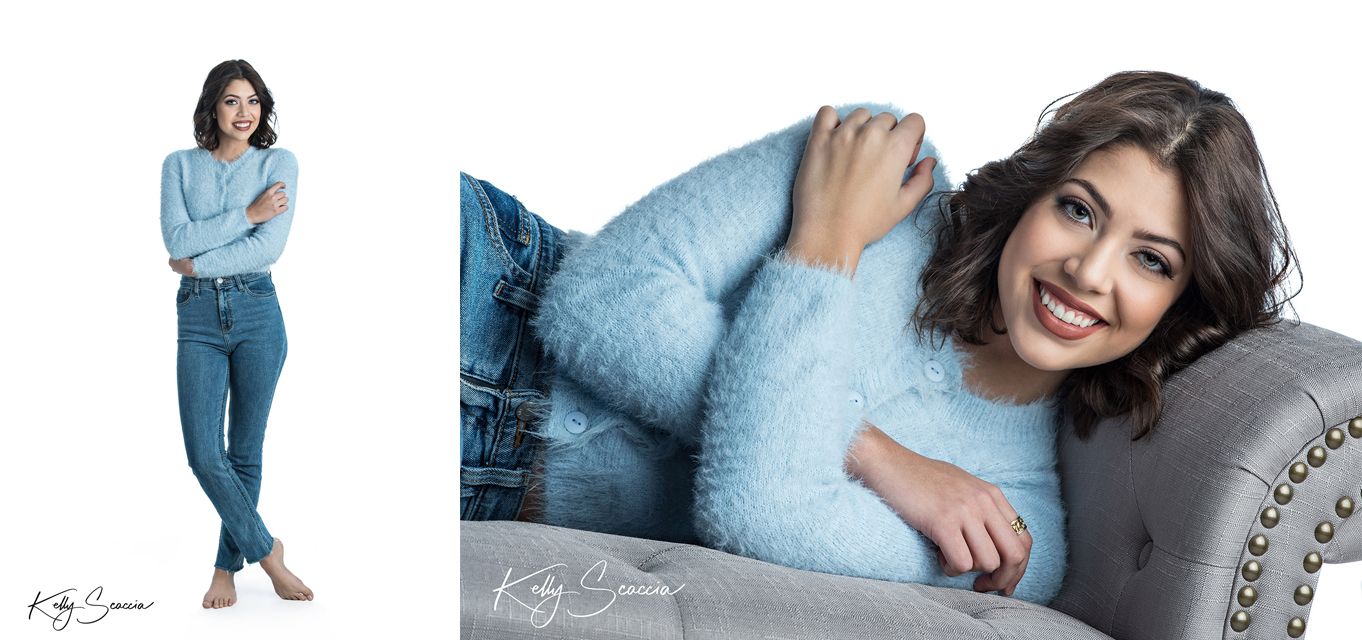 High School senior girl in studio on a white background smiling in a light blue sweater laying on a taupe couch
